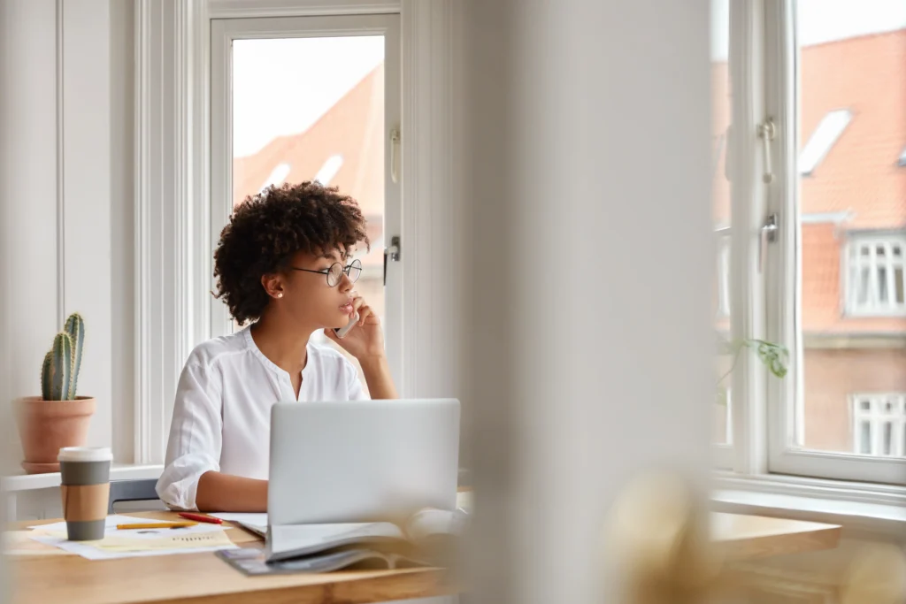 photo female entrepreneur speaks via cell phone looks thoughtfully into window analyzes paperwork from accounting department photo female entrepreneur speaks via cell phone looks thoughtfully into window analyzes paperwork from accounting department