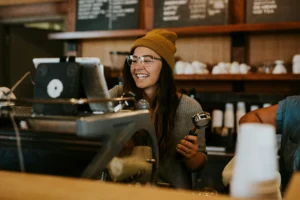 mulher branca de cabelos longos castanhos usando touca trabalhando em um café sob o contrato intermitente de trabalho