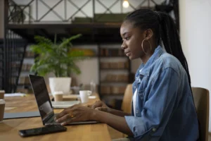 mulher negra de trancas longas e blusa jeans azul usando computador e implementando a mulher negra de tranças longas e blusa jeans azul usando computador e implementando a inteligência artificial no RH