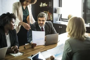 quatro pessoas reunidas em uma mesa de um escritório de advocacia lendo um papel. ponto digital para escritório de advocacia