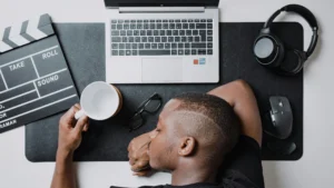 um homem sentado em uma mesa com um laptop e fones de ouvido - 10 sinais do burnout