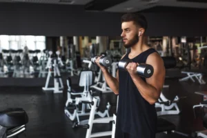 homem branco de cabelo preto e barba na academia treinando os bíceps levantando peso - ponto digital para academia