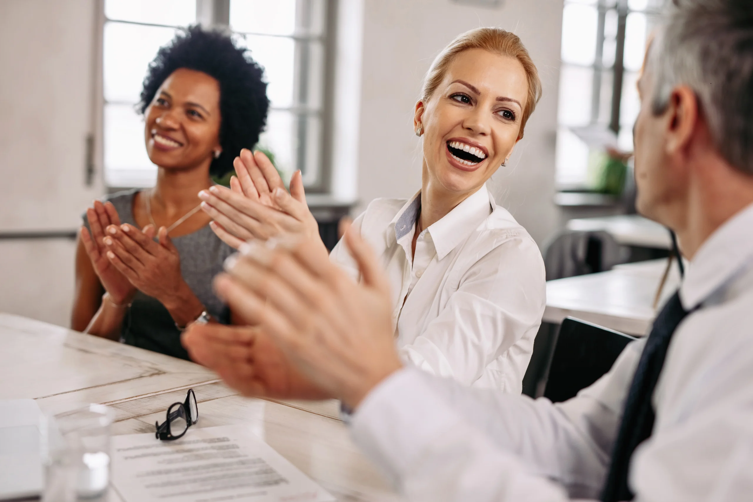 feliz empresaria e seus colegas de trabalho batendo palmas em uma reuniao no escritorio scaled feliz empresaria e seus colegas de trabalho batendo palmas em uma reuniao no escritorio scaled