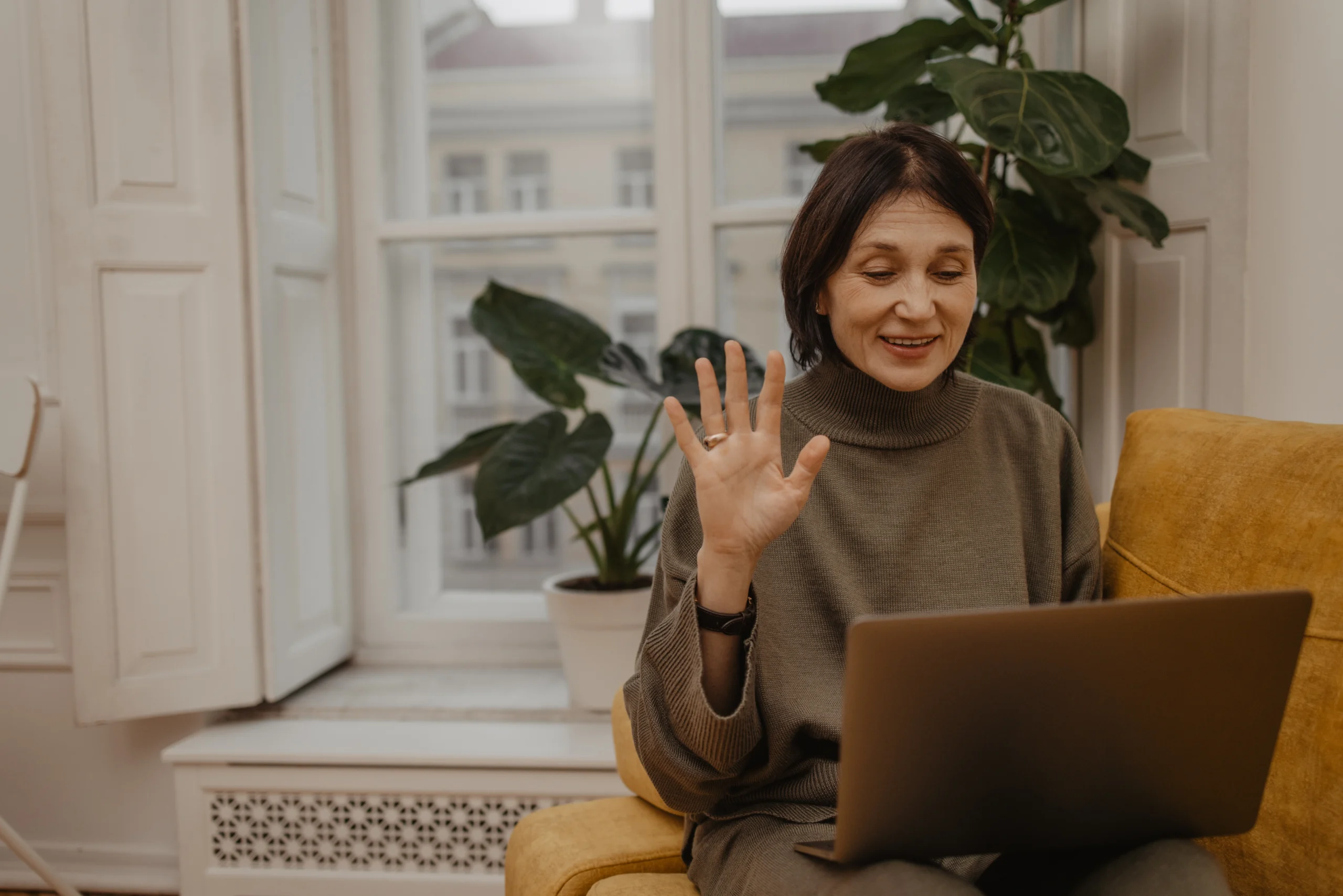 happy middle aged caucasian woman sitting sofa holding laptop while having video call with family friends scaled happy middle aged caucasian woman sitting sofa holding laptop while having video call with family friends scaled