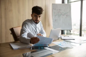 trabalhador de escritorio usando graficos de financas Bottom line