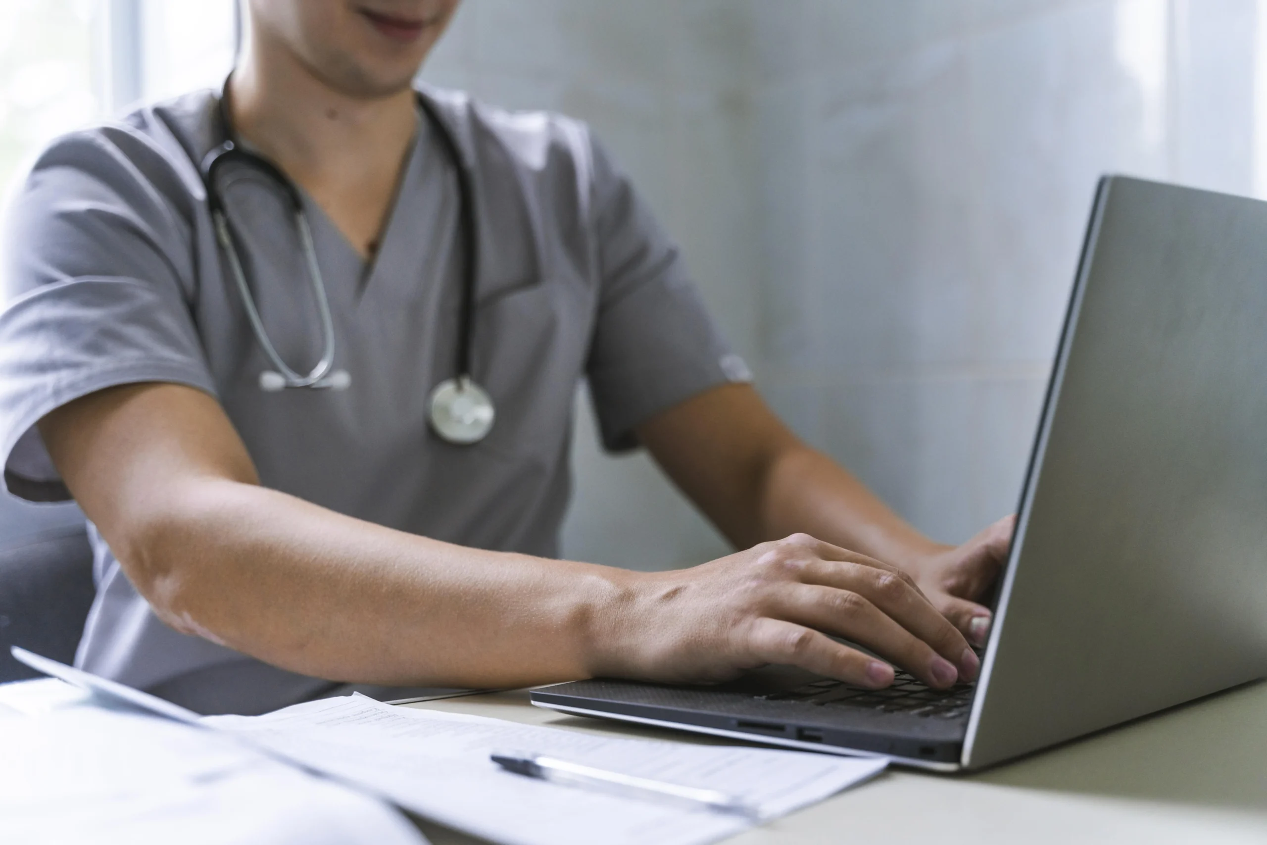 vista lateral medico com estetoscopio trabalhando no laptop scaled vista lateral medico com estetoscopio trabalhando no laptop scaled