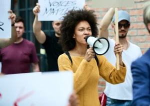 mulher negra de cabelos crespos e blusa amarela protestando em greve