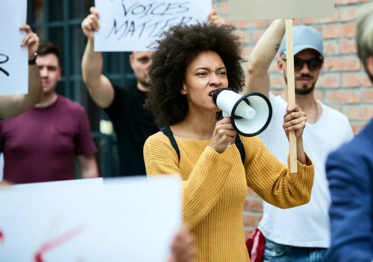 mulher negra descontente participando de manifestacoes anti racismo e gritando pelo megafone