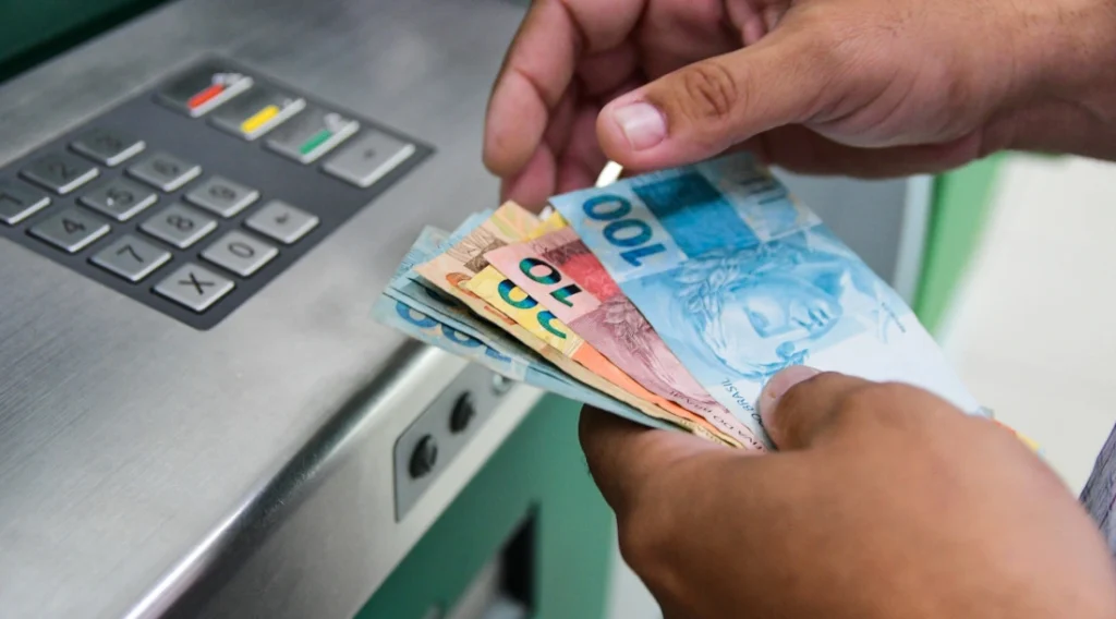 Pessoa sacando dinheiro em sua conta salário após fazer a abertura Pessoa sacando dinheiro em sua conta salário após fazer a abertura