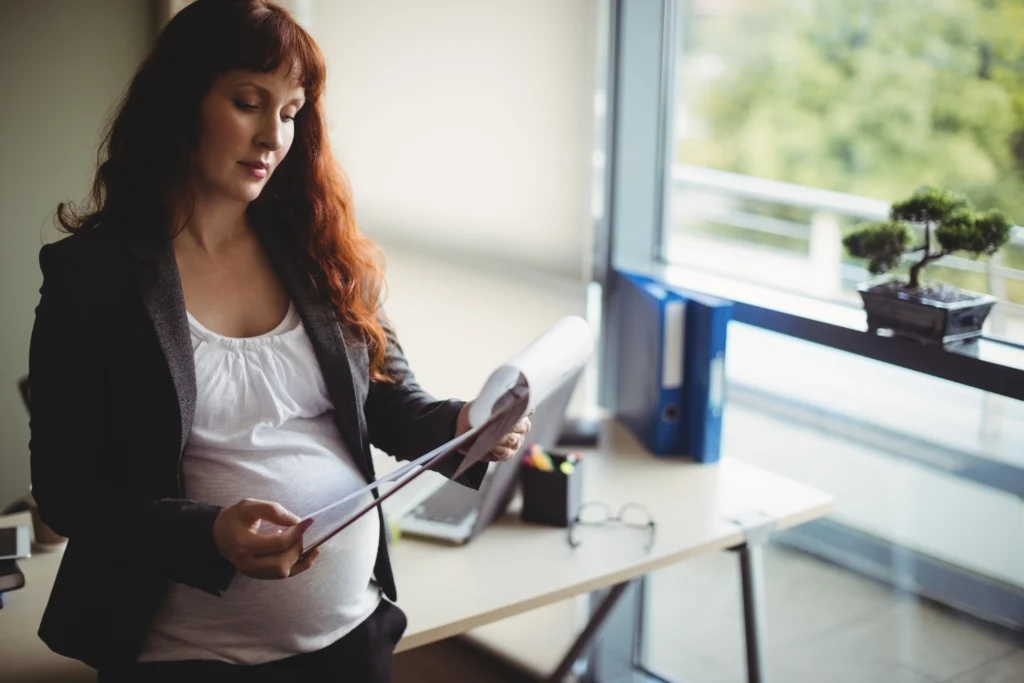 pregnant businesswoman reading paper documents pregnant businesswoman reading paper documents